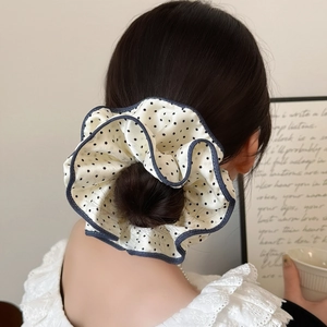 Elegant polka dot scrunchie in beige fabric with black spots on a soft bun hairstyle