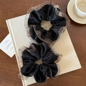 Set of two black scrunchies with leopard print lace edges on a French aesthetic background
