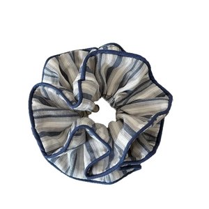 Blue and white striped scrunchie with dark blue piped edges on a clean white background