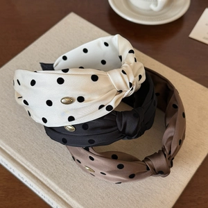 Polka dot knoop haarbanden in ivoor, zwart en karamel op een houten bureau