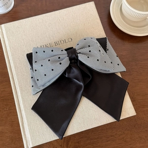 Detail view of double-layered striped bow hair clip with black ribbons on a book