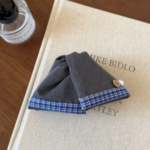 Détail d'une pince à cheveux en denim gris avec bordure à carreaux, perle et bouton