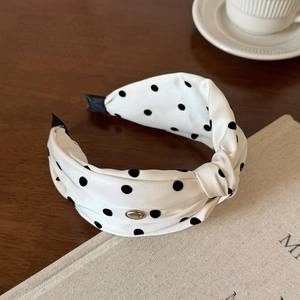 Detailopname van retro hoofdband met stippen in zijden textuur en gouden label