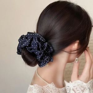 Detail of navy blue floral scrunchie worn on low bun with small gold pendant