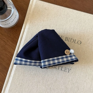 Détail d'une pince à cheveux en tissu bleu marine avec bouton vintage et perle décorative