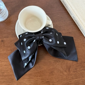 Detailed view of elegant black polka dot satin bow hair claw with long ribbon streamers