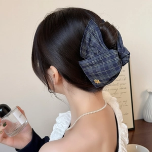 British style navy plaid bow hair claw clip with gold bee detail worn by a model