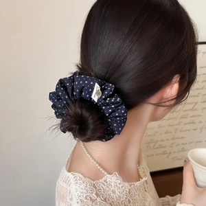 Elegant navy blue floral scrunchie with handmade label on a stylish bun hairstyle