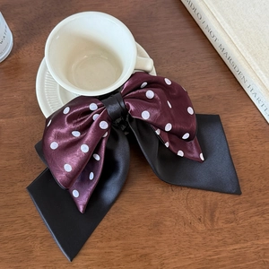 Elegant polka dot satin hair bow clip showing glossy silk texture and luxury style