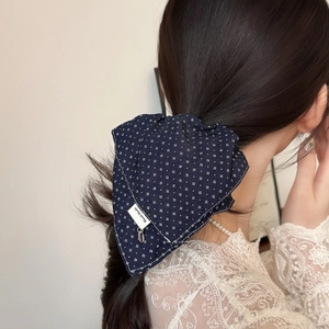 Elegant navy blue pleated scrunchie with white polka dots on a low ponytail