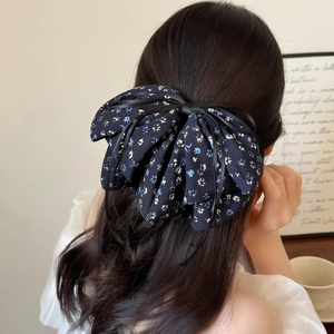 Elegant navy floral fabric bow hair clip for women styled on dark long hair back view