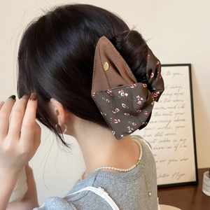 Detail of elegant French floral fabric shark clip shown on a model hair bun