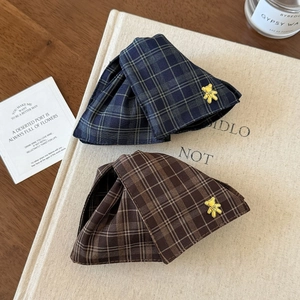Detailed macro view of British style plaid fabric hair clips with gold bear metal accents