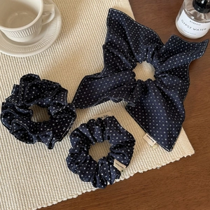 Navy blue patterned hair scrunchie set with bow and handmade label on textured mat