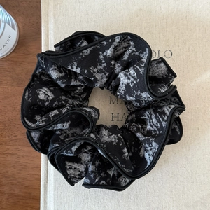 Detail of black and white ink marble scrunchie on a book showing soft chiffon texture