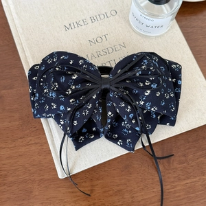 Detail of floral navy blue bow hair clip showing multi-layer chiffon texture and ribbon