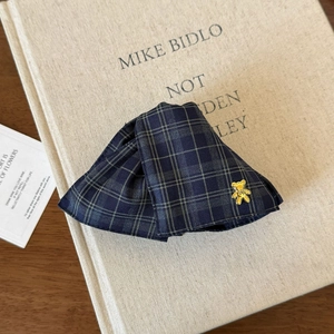 Detail of navy plaid bow hair claw with a golden bear charm on a vintage book