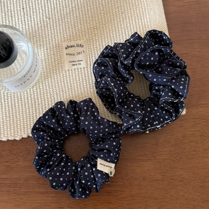 Detail of navy blue floral scrunchies with handmade label and metal charm on wood