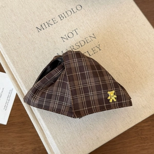 Detailed close-up of brown plaid fabric hair claw with a gold metal bear ornament