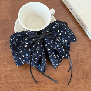 Floral navy blue fabric bow hair clip with ribbons on rustic wooden background