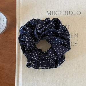 Detail of dark blue floral scrunchie with a gold metal charm on a vintage book