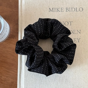 Detail view of a black polka dot scrunchie on a book for a French aesthetic look