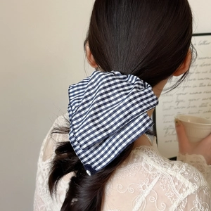 Blue and white gingham checkered bow hair tie worn on elegant hairstyle in cafe setting