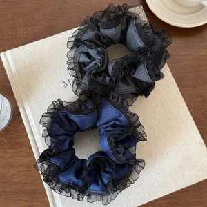 Gros plan d'un lot de chouchous à bordure dentelle bleu marine et gris sur un livre