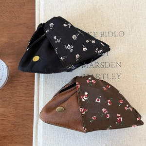 Detail view of floral fabric triangle hair clips with premium golden logo plates