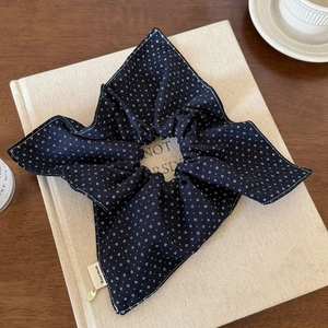 Detail of navy blue pleated scrunchie with handmade label and small golden pendant