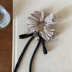 Detailopname van champagne satijnen scrunchie met zwarte linten en parel hanger