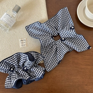 Detail of blue gingham checkered fabric scrunchies on a wooden table for daily hair styling