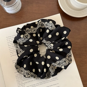 Detail of black polka dot and lace scrunchie placed on an open book and coffee table
