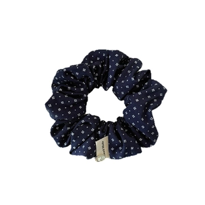 Navy blue pleated floral scrunchie with white patterns and handmade metal pendant