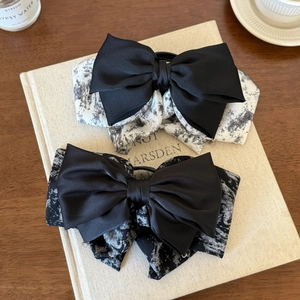 Elegant multi-layer bow hair clip with ink print pattern on a vintage book