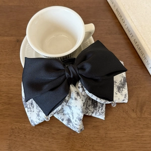 Detail of multi-layer bow hair clip with ink print pattern and crystal pendants