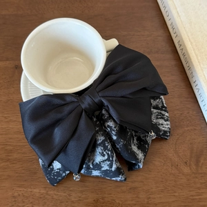 Close-up of tiered black satin bow hair clip with ink print lining and crystal charms