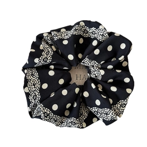 Polka dot black scrunchie with white lace edges and brand label for hair styling
