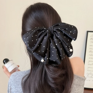 Elegant black bow hair clip with white heart dots and hanging pearls on a model