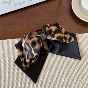 Detail of leopard print bow hair clip with satin fabric and sparkling rhinestone center