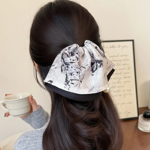 Elegant ink-wash satin bow hair claw with pearl detail on model's ponytail