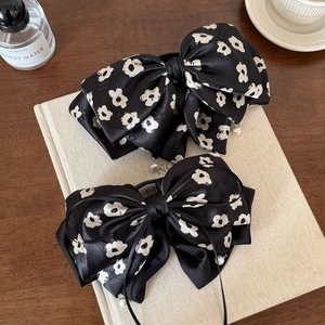 Pince à cheveux nœud satin fleuri avec perles blanches sur fond de livre ancien