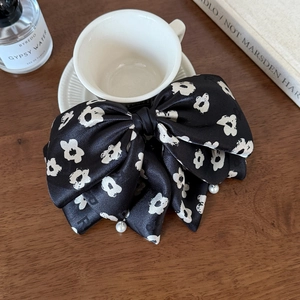 Détail du nœud en satin noir fleuri avec d'élégantes perles sur un bureau en bois