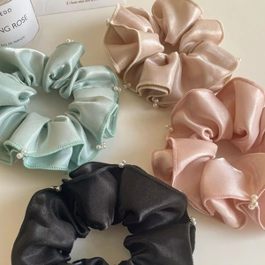 Gros plan de quatre chouchous en satin avec perles blanches en vert pastel, rose et or