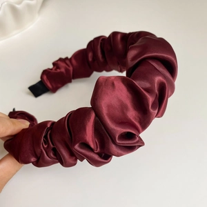 Détail d'un serre-tête en satin plissé bordeaux montrant la texture et les embouts antidérapants
