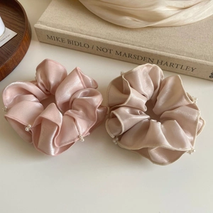 Détail des chouchous en satin rose et champagne avec des bords élégants en perles nacrées