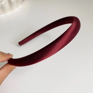 Détail du serre-tête en satin bordeaux montrant la texture lisse et le design rembourré