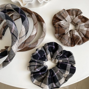 Detailed close-up of brown and gray plaid tweed hair scrunchies and wide padded headbands