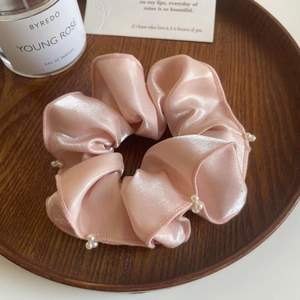 Chouchou en satin rose orné de perles blanches dans un décor élégant et raffiné