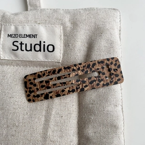 Detailed macro view of rectangle leopard print hair clip on a canvas texture background